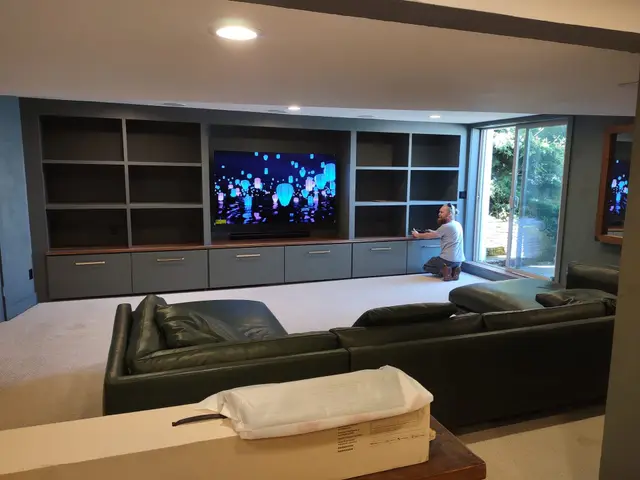 Finished media room with custom built-in TV wall and leather sectional near Estacada, OR — Devine Home Remodeling & Construction