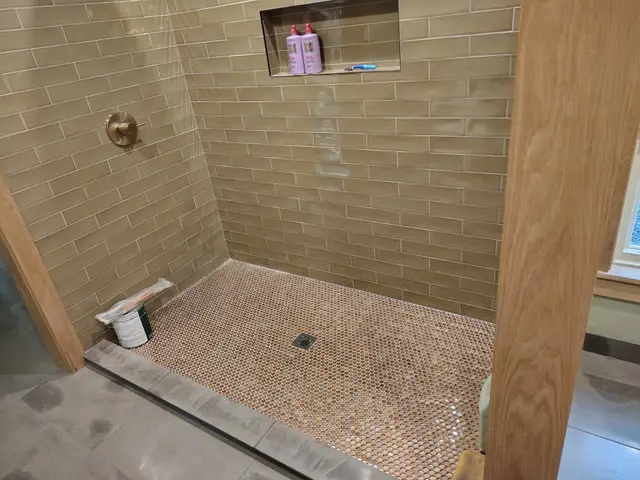 Curbless shower floor with penny mosaic tile and matching wall tile detail near Estacada, OR — Devine Home Remodeling & Construction