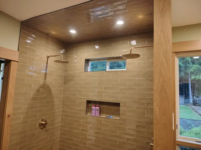 Walk-in shower with full-height taupe tile, dual rain heads, and recessed niche near Estacada, OR — Devine Home Remodeling & Construction