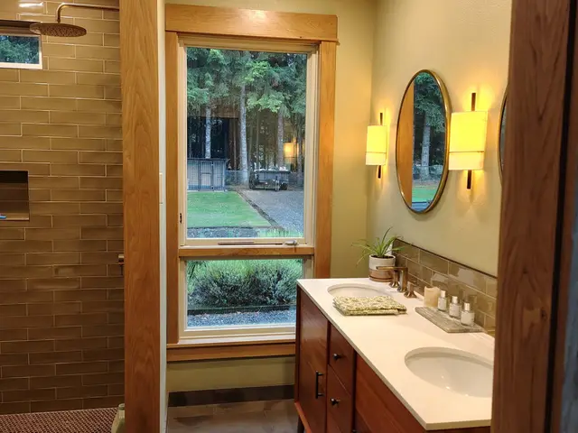 Custom double vanity with warm wood cabinetry, quartz counters, and round mirrors near Estacada, OR — Devine Home Remodeling & Construction
